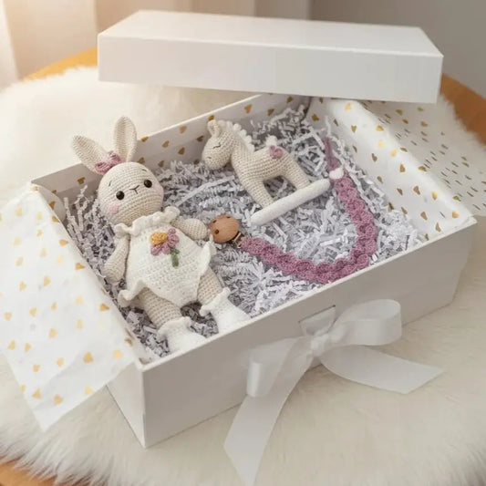 Crocheted bunny and unicorn in a gift box with pink accents and confetti paper