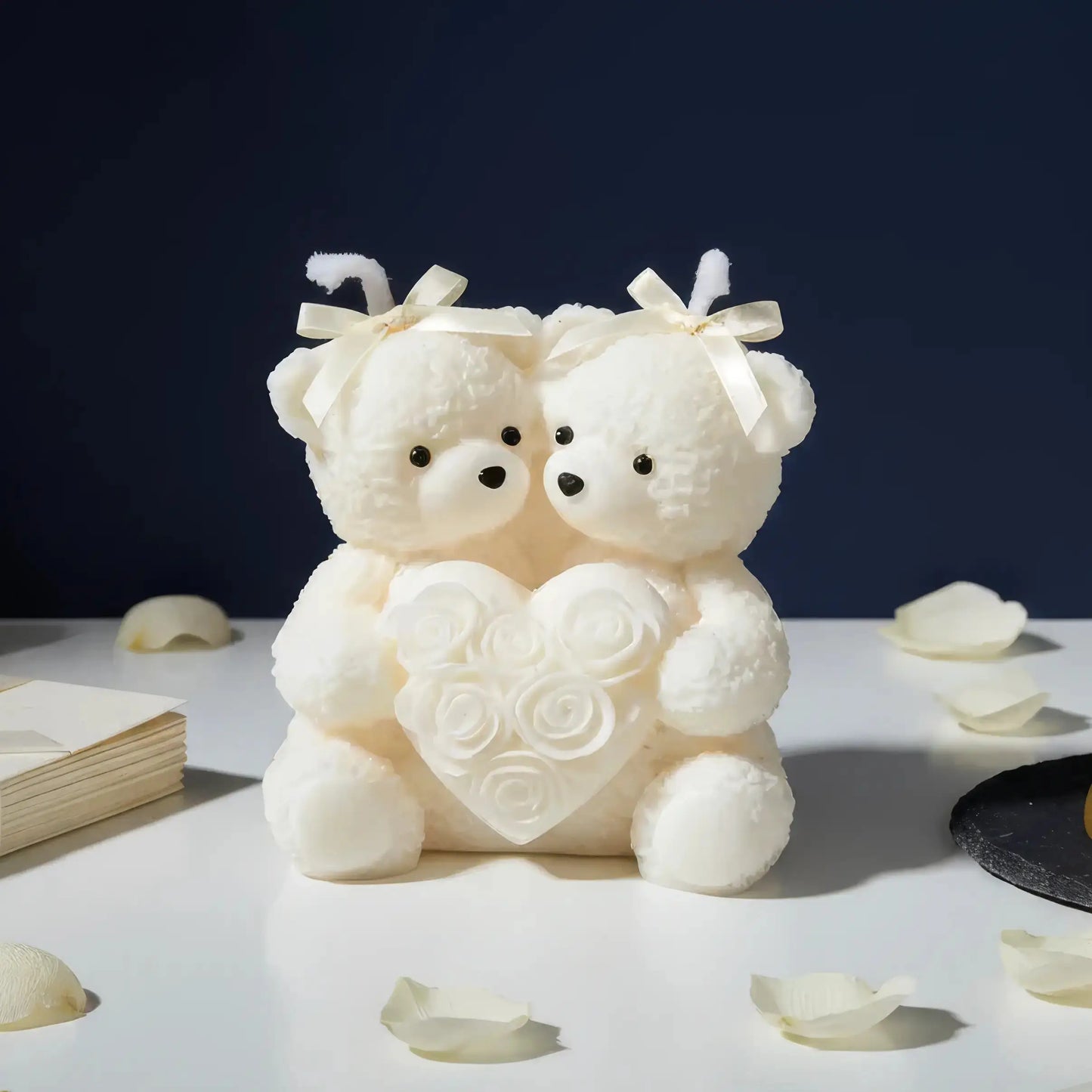 Two white teddy bears holding a heart with rose petals on a dark background