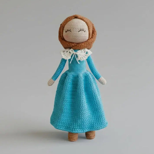 Crocheted doll in blue dress with white collar, brown hair, closed eyes
