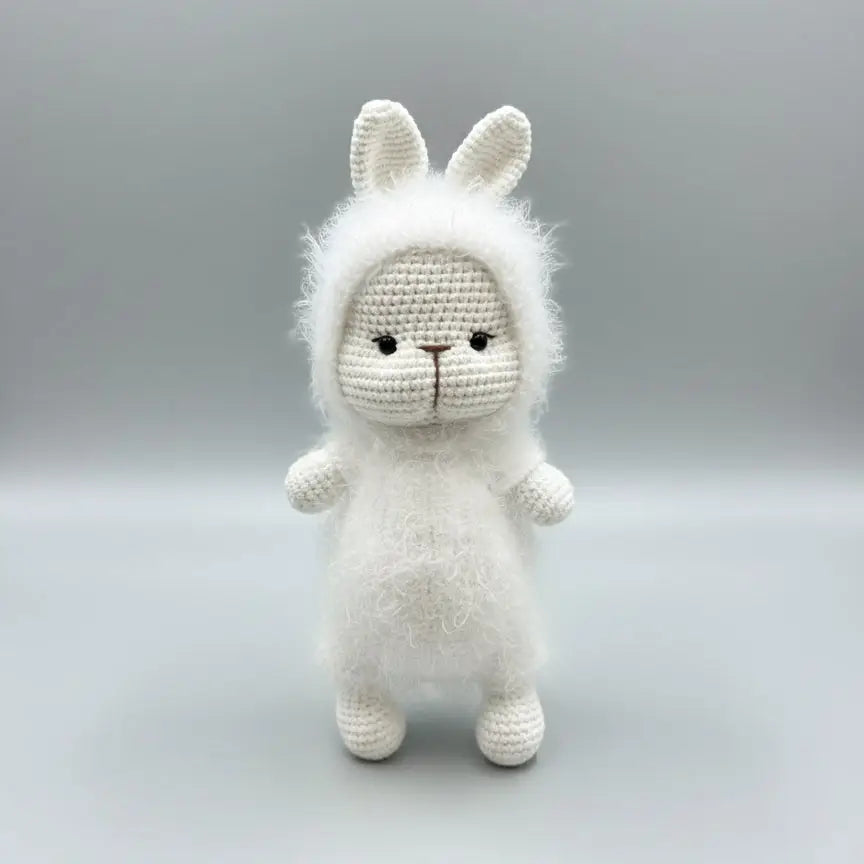 Fluffy white crocheted bunny with fuzzy mane, standing against a gray background.