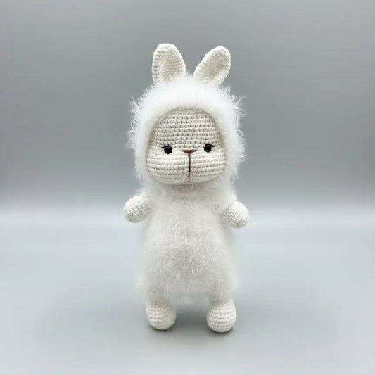 Fluffy white crocheted bunny with fuzzy mane, standing against a gray background.
