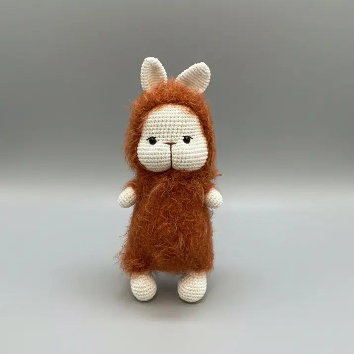 Crocheted bunny with fluffy orange-brown fur and white body, standing upright