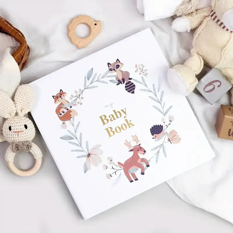 Whimsical baby book with woodland animals in floral wreath, surrounded by soft toys