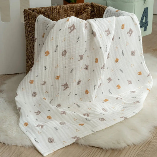 White baby blanket with animal pattern draped over a basket on a wooden floor.