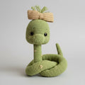 Green crocheted snake toy with bow, curled up on neutral background