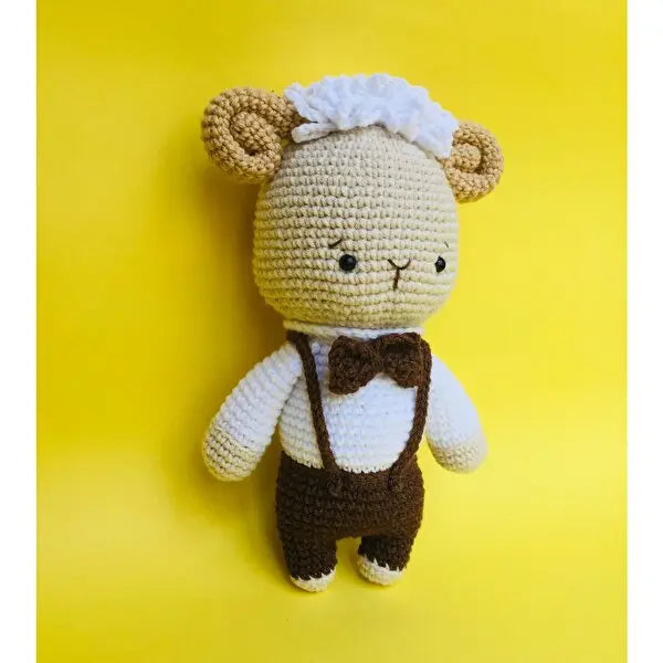 a crocheted teddy bear wearing a brown bow tie