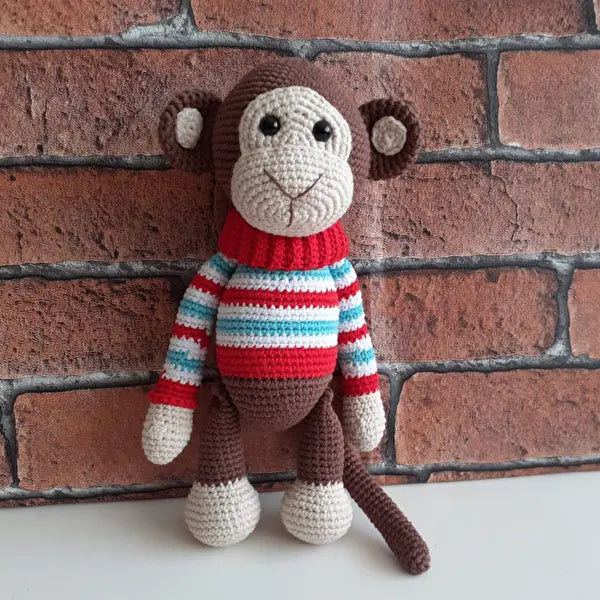 a crocheted monkey wearing a striped sweater