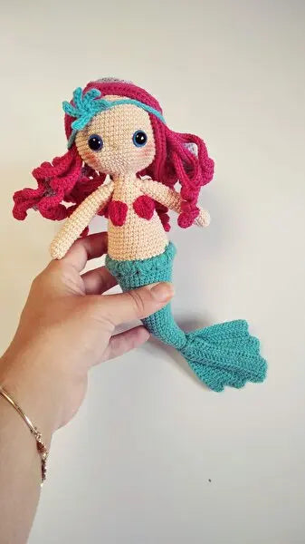 a hand holding a crocheted little mermaid doll