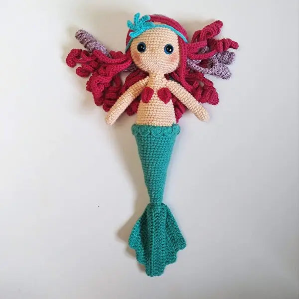 a crocheted mermaid doll hanging on a wall