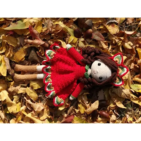 a knitted doll laying on top of a pile of leaves