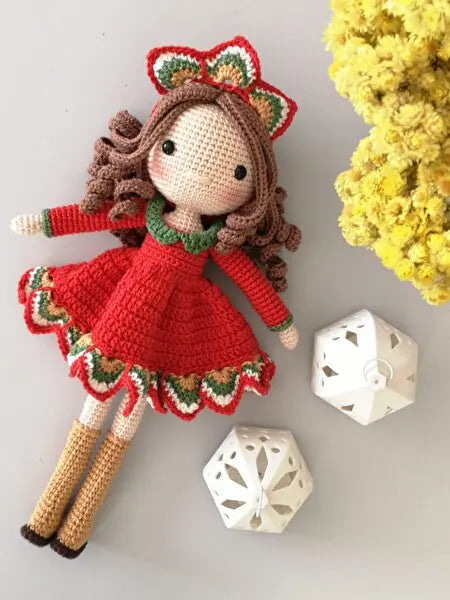 a crocheted doll next to a white dice