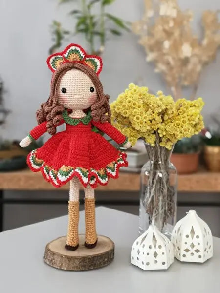 a crocheted doll next to a vase of flowers