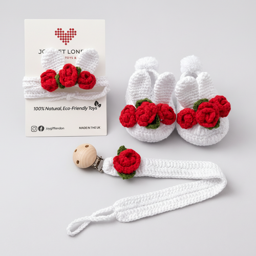 White crocheted baby booties with red rose details and a matching pacifier clip, alongside a Jory & Lona packaging card.