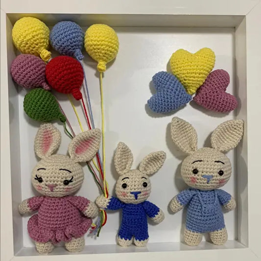 a group of crocheted rabbits holding balloons