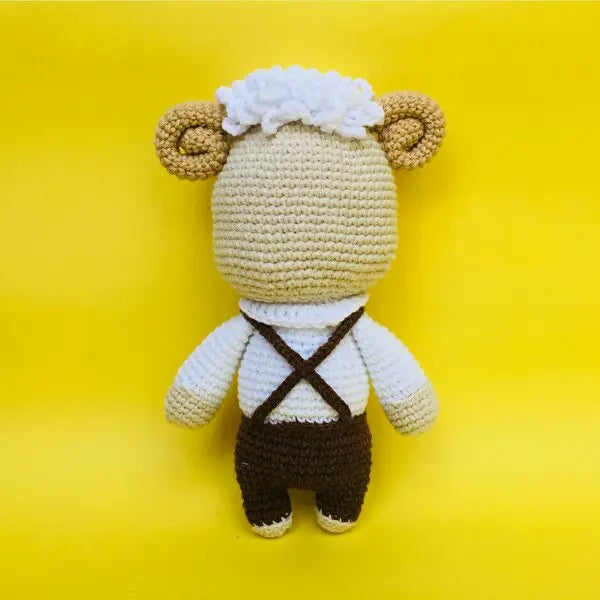 a crocheted stuffed animal wearing a brown suspender