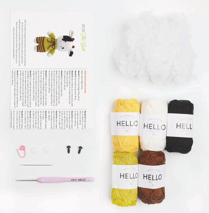 Knitting supplies with colorful yarn skeins labeled "Hello" and a crochet hook