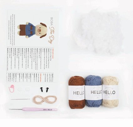 Knitting supplies: three Hello yarn skeins in brown, blue, and cream with crochet hook