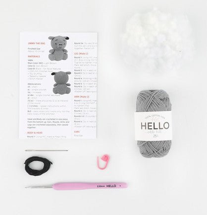 Crochet supplies laid out with pattern, gray yarn, pink hook, and black elastic