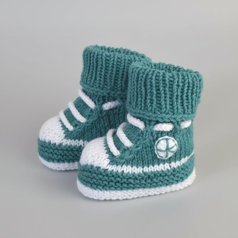 Handknit teal and white baby booties with athletic shoe design and laces