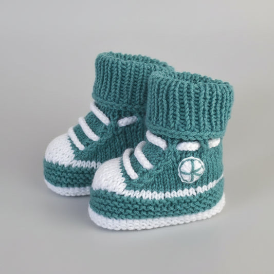 Handknit teal and white baby booties with athletic shoe design and laces