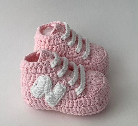 Pink crocheted baby booties with white decorative knitted bows