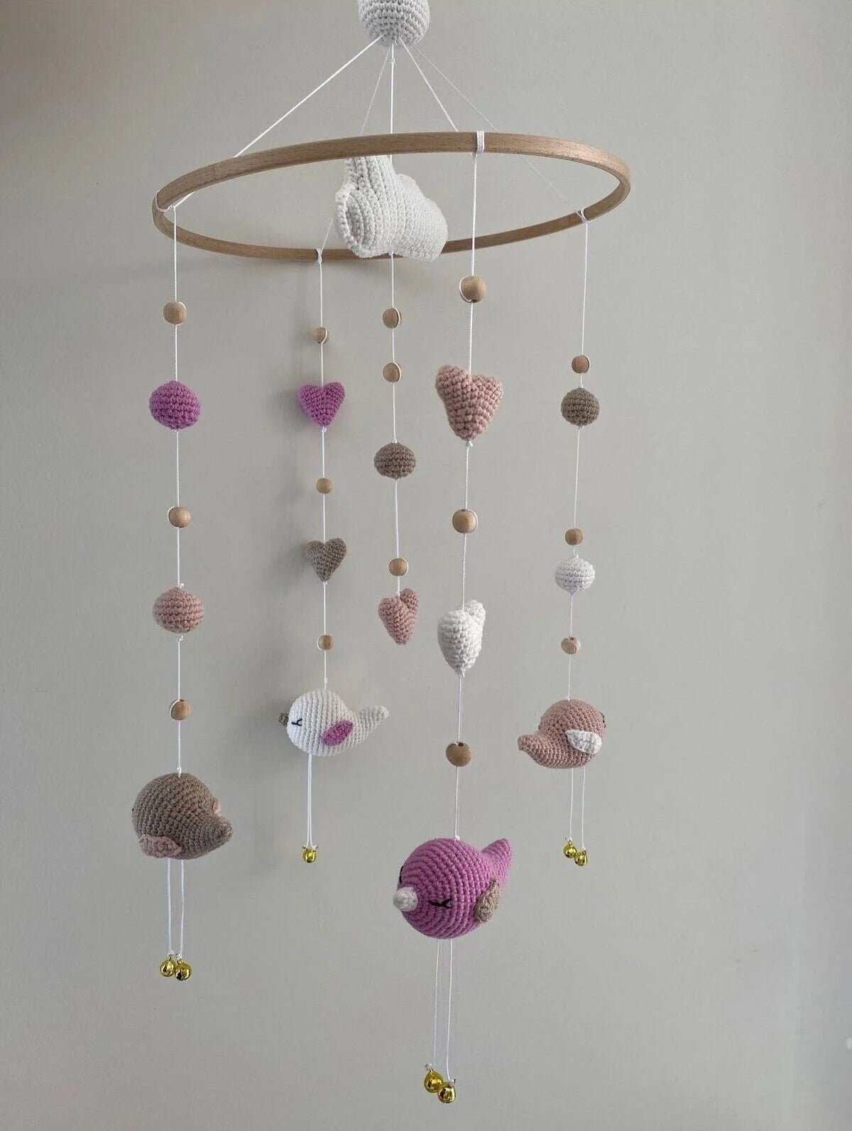 Crocheted baby mobile with hearts, birds, and wooden beads in pastel colors