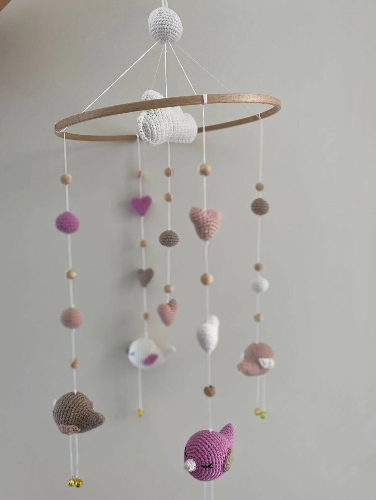 Crocheted baby mobile with hearts, clouds, and fish in pastel pink, white, and gray