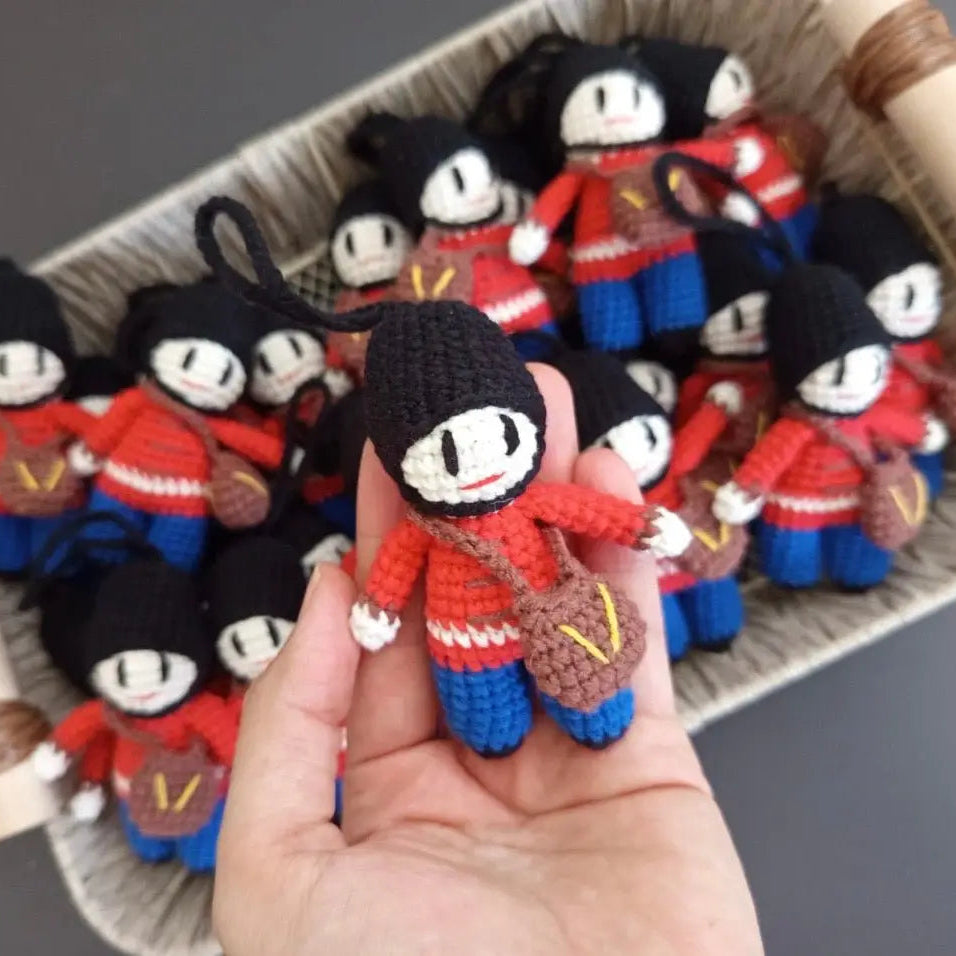 Crocheted dolls in red and blue uniforms with black hair in a basket and hand