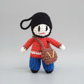 Crocheted mini dolls in red and blue uniforms with black heads, held in a hand