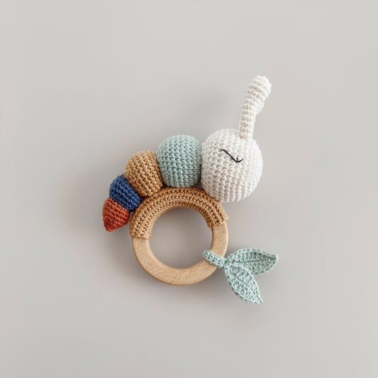 Crocheted bunny teething ring with colorful segments, held by hand near "hello world" sign