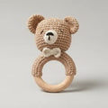 Crocheted teddy bear rattle with wooden teething ring on neutral background