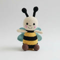 Crocheted bee plushie with smiling face, black antennae, and teal wings