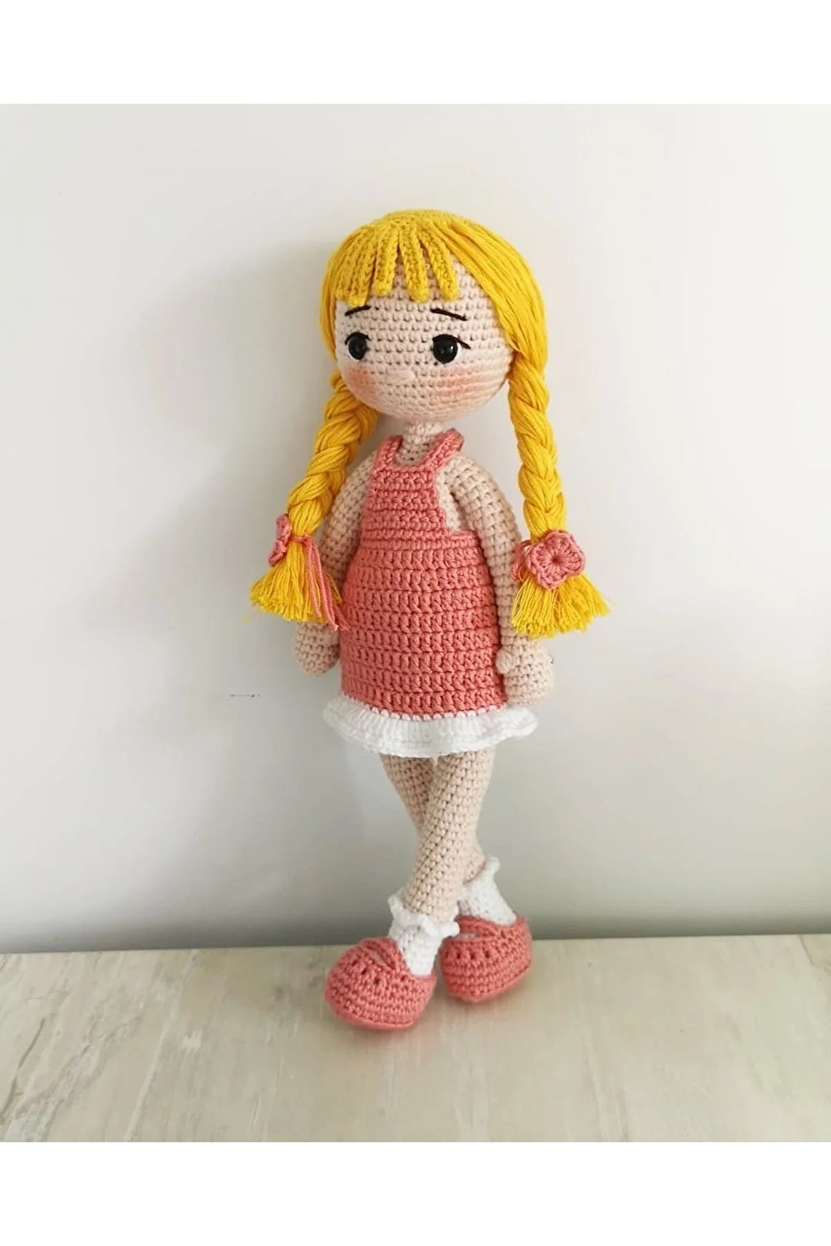 Crocheted doll with yellow braids, pink dress, white trim, and coral shoes