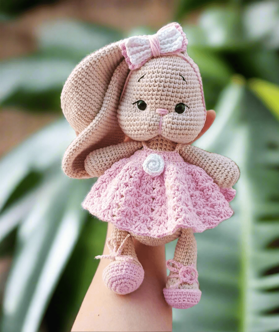Crocheted pink bunny with bow, wearing a delicate lace dress and booties
