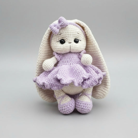 Crocheted bunny in lavender dress with bow, sitting against neutral background