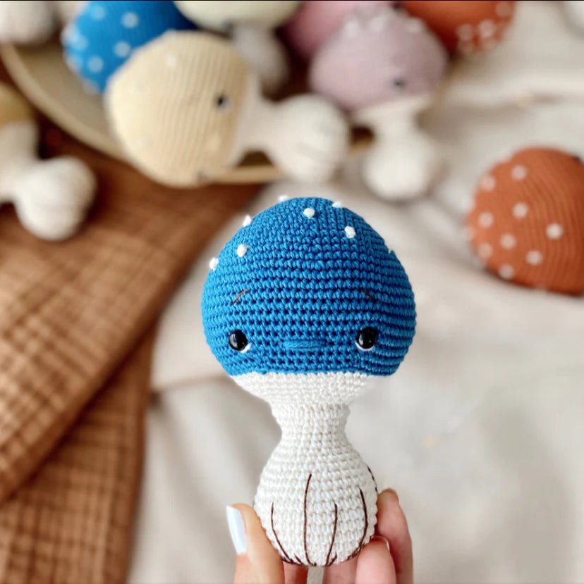 Blue and white crocheted mushroom toy with polka dots, held by a hand