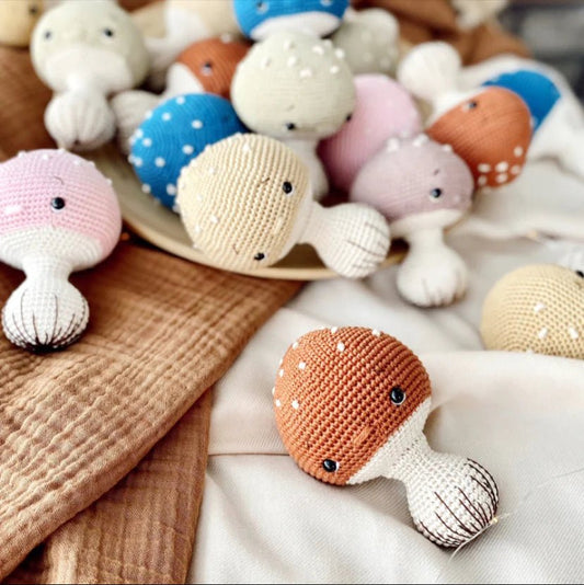 Crocheted soft toys in pastel colors scattered on wooden and white fabric surface