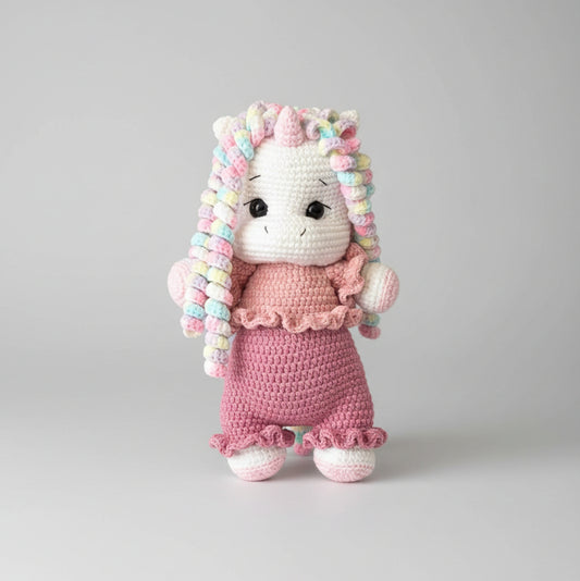 Crocheted unicorn doll in pink dress with colorful curly mane and tail