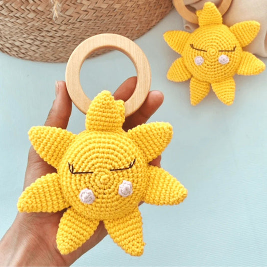 Crocheted yellow sun-shaped baby teether with wooden ring, cute sleepy face design