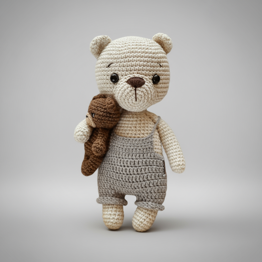 Crocheted teddy bear in gray overalls, holding a small brown stuffed animal friend.