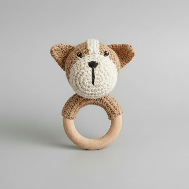 Crocheted teddy bear rattle with wooden teething ring on neutral background