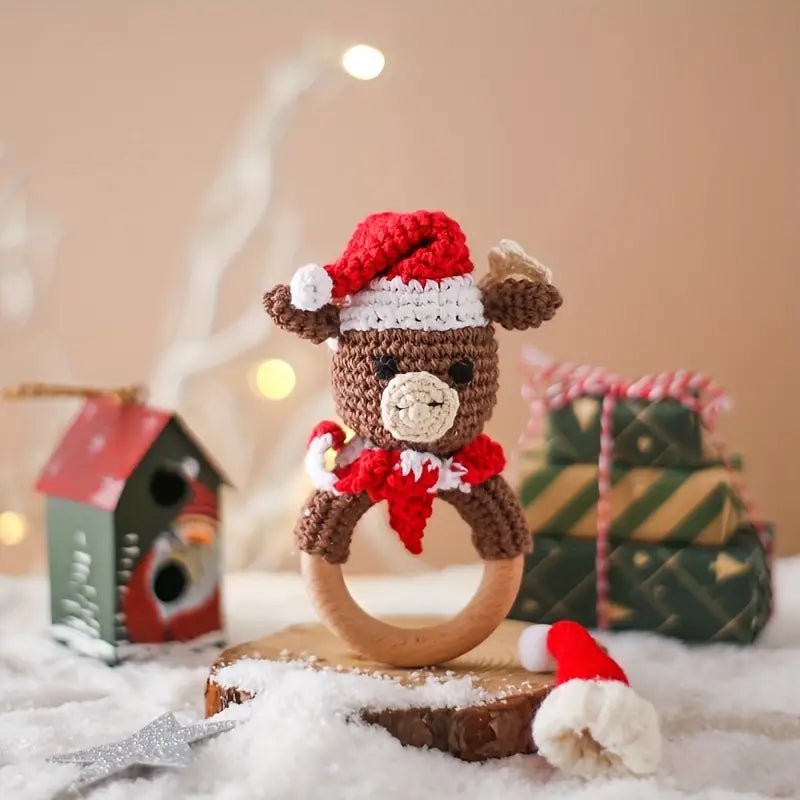 Crocheted teddy bear with Santa hat on wooden ring, surrounded by Christmas gifts and snow