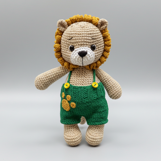 Crocheted lion stuffed animal wearing green overalls with yellow buttons