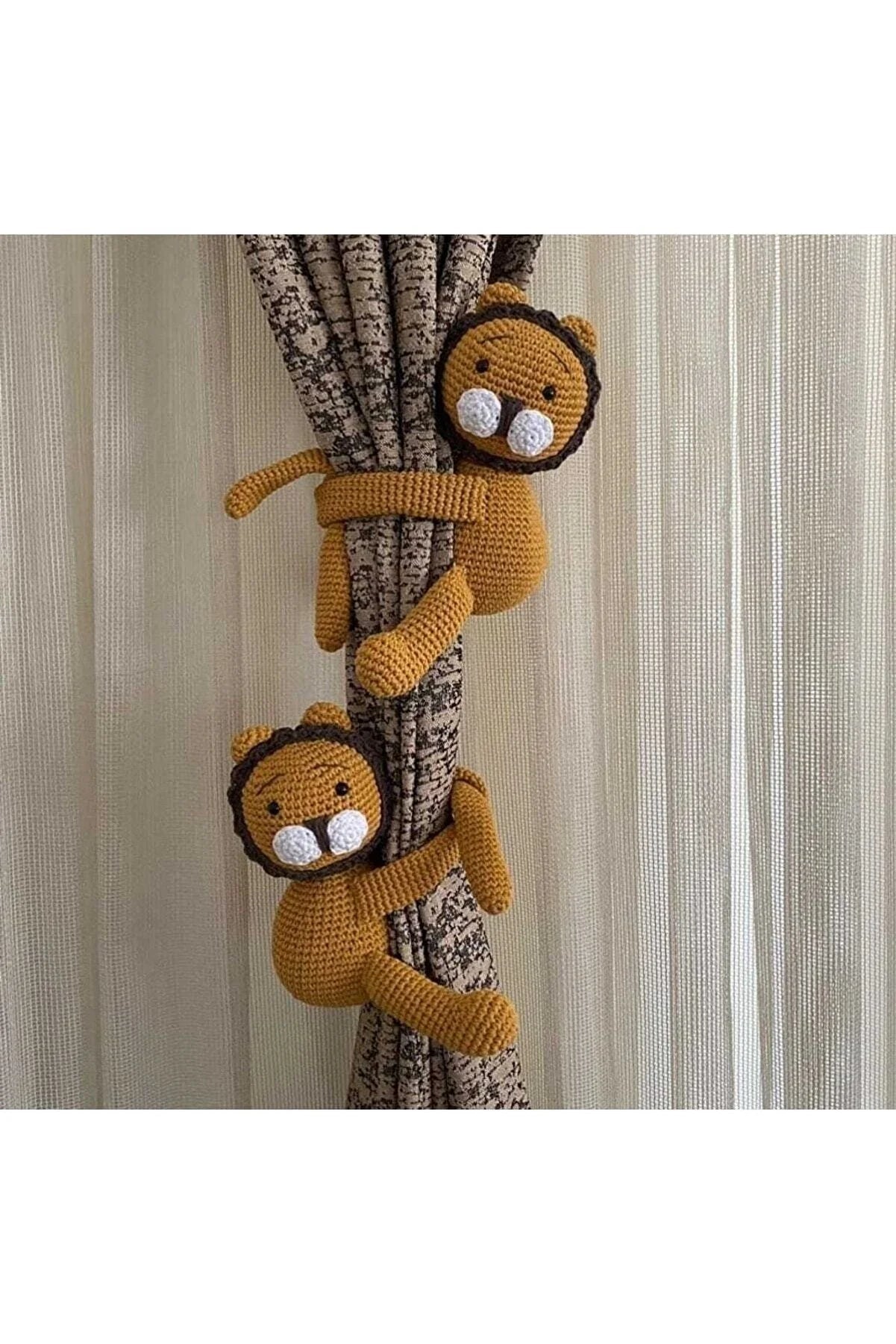 Two crocheted yellow lions hugging a textured curtain rod against light curtains