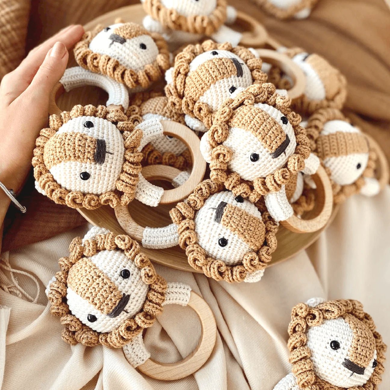 Crocheted lion baby rattles with wooden rings, in soft beige and white yarn colors