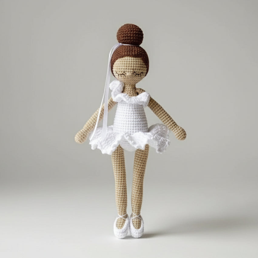 Crocheted ballerina doll with white tutu and bun hairstyle in soft beige and white yarn