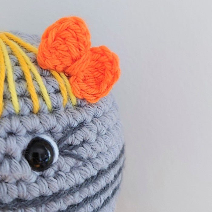 Crocheted bird with orange crest, black eye, gray body, and yellow highlights