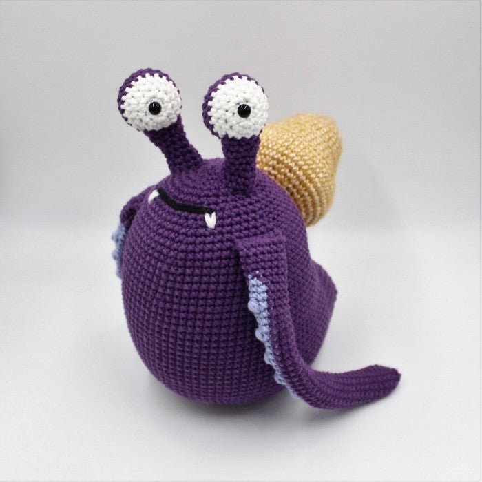Crocheted purple snail with googly eyes and a yellow shell, handmade amigurumi toy
