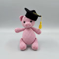 Pink crocheted pig wearing a black graduation cap with yellow tassel