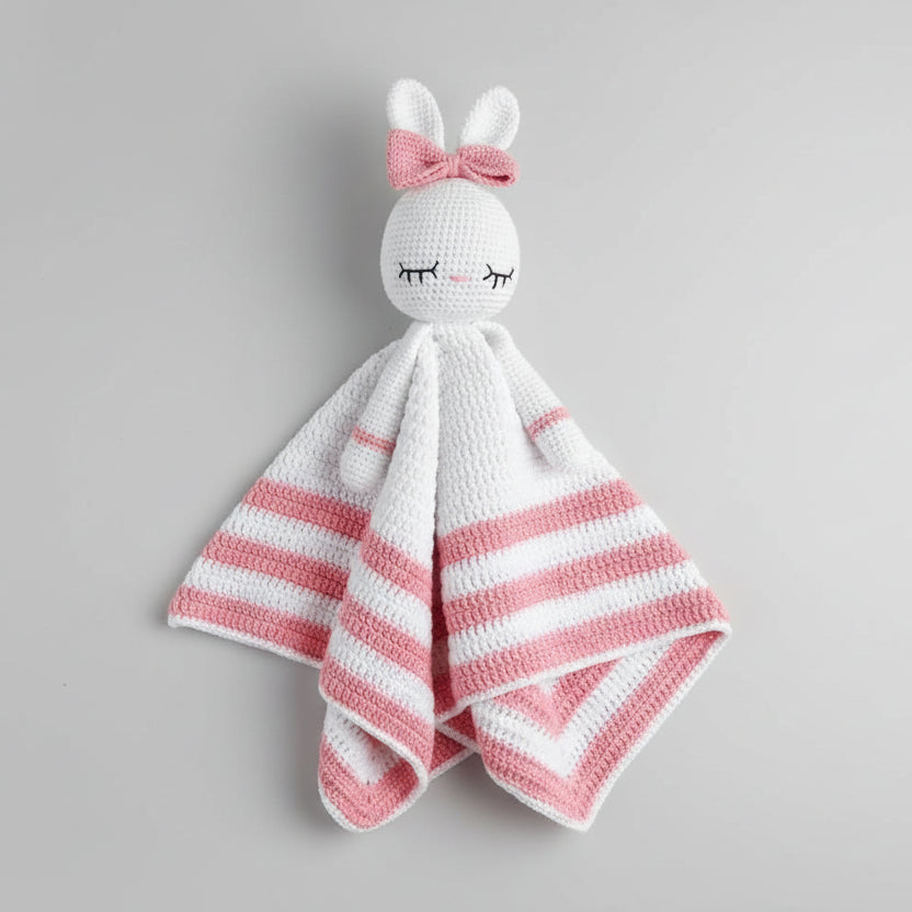 Crocheted bunny lovey with pink and white stripes, closed eyes, and a bow